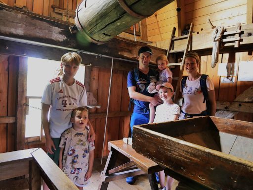 Familie steht in einem rustikalen Raum mit Holzansichten und Fenstern.