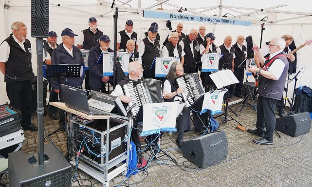 Eine Band mit Sängern und Musikern, die live auf einer Bühne auftreten.