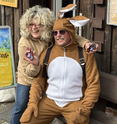 Entspannte Organisatoren mit hochprozentigem zum Aufwärmen Ein Mann im Hasenkostüm sitzt neben einer Frau mit lockigem Haar, beide lächeln.
