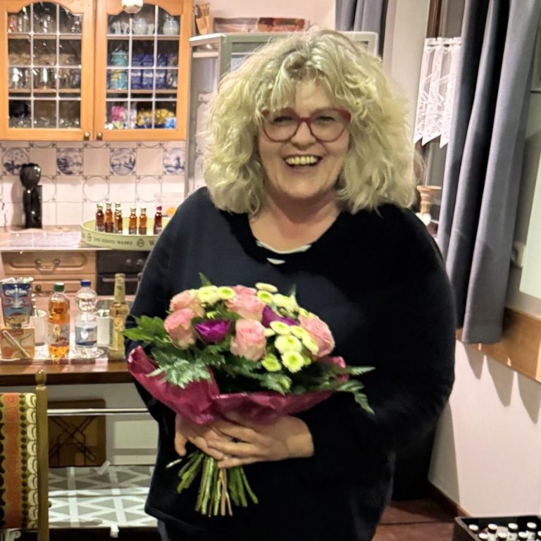 Lydia Ufen hat am 23. März 2026 als Dank für viele Jahre unermüdlichen Einsatz im Bereich Catering in der Mühle einen Blumenstrauß erhalten Frau mit lockigem Haar hält einen Strauß mit bunten Blumen in der Hand.