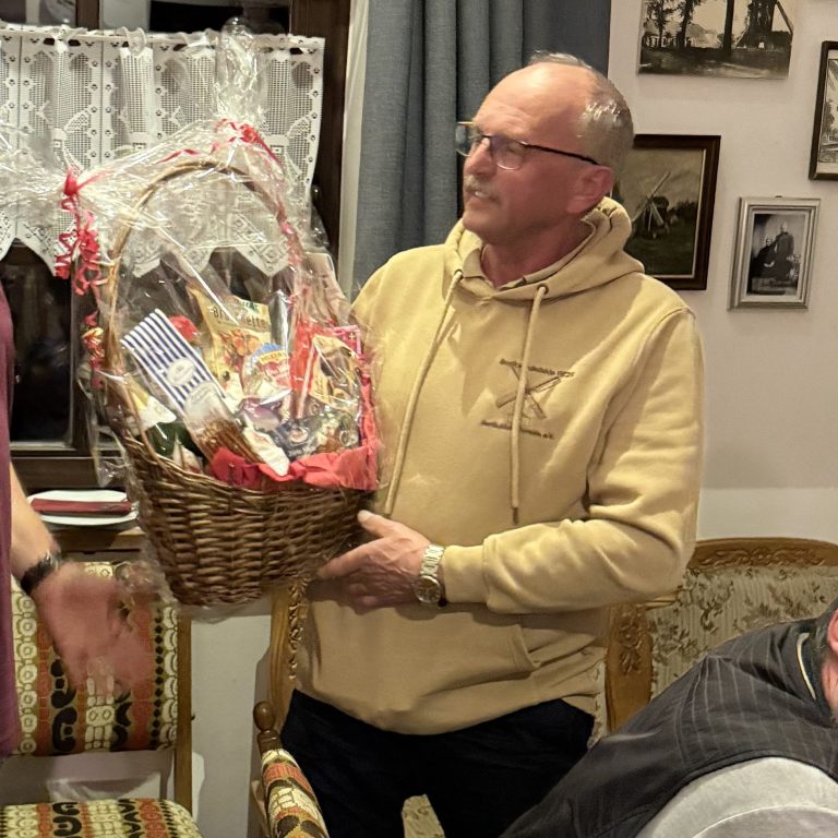 Wilhelm Broeksmid hat am 23. März 2026 als Dank für 14 Jahre Vorstandsarbeit in der Mühle einen Präsentkorb überreicht bekommen Ein Mann hält einen Geschenkkorb mit verschiedenen Artikeln und schaut zur Seite.