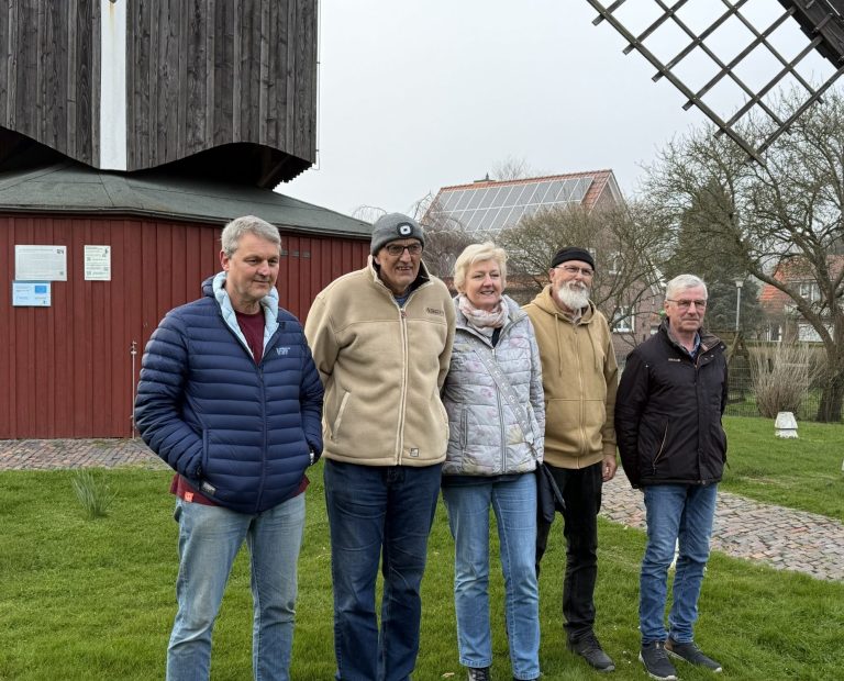 Fünf Personen stehen lächelnd vor einer windmühlenähnlichen Struktur. Gezeigt werden die Vorstandsmitglieder