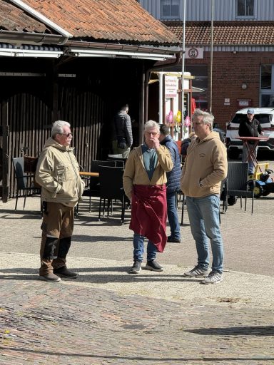 Mitglieder bei einer Pause Drei Personen im Gespräch vor einem historischen Gebäude, bei klarem Wetter.