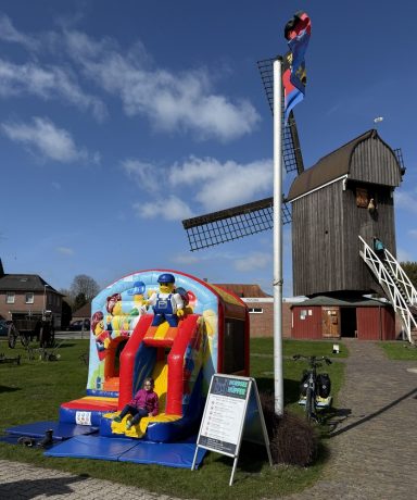 Hüpfburg für die Kinder Bunte Hüpfburg neben einer Windmühle auf einem grünen Feld.